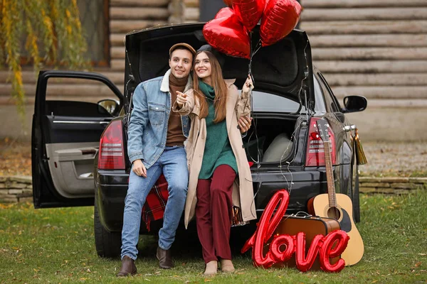 Joyeux jeune couple avec voiture et ballons à air dans le parc. Fête de la Saint-Valentin — Photo