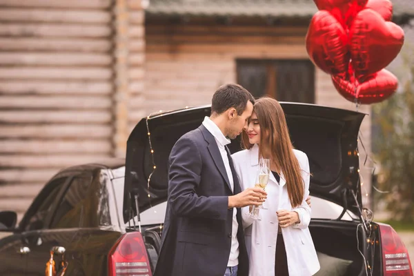 Gelukkig jong stel drinken champagne in de buurt van auto buiten. Valentijnsdag — Stockfoto