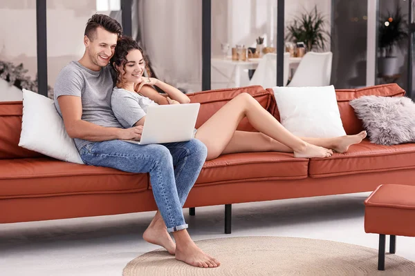 Счастливая молодая пара с ноутбуком дома — стоковое фото