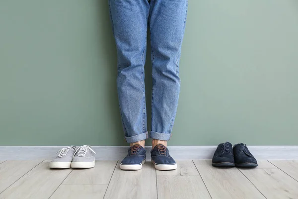 Νεαρός άνδρας με διαφορετικά κομψά παπούτσια κοντά στον τοίχο χρώμα — Φωτογραφία Αρχείου