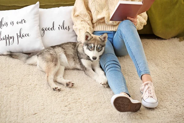 Young woman with funny husky puppy reading book at home — Stock Photo, Image