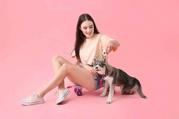 Mujer linda con divertido husky cachorro y monopatín sobre fondo de color — Foto de Stock