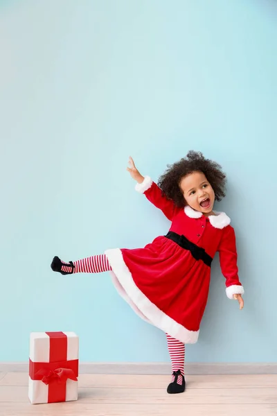Little African-American girl in Santa costume near color wall — Stock Photo, Image