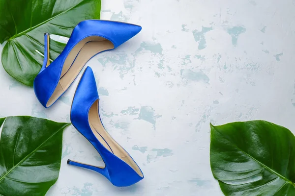 Stylish female shoes and tropical leaves on light background — ストック写真