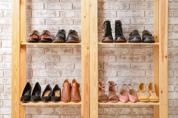 Unidade de prateleira com sapatos elegantes perto da parede de tijolo — Fotografia de Stock