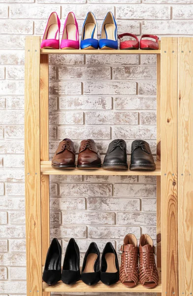 Shelf unit with stylish shoes near brick wall — Stock Photo, Image