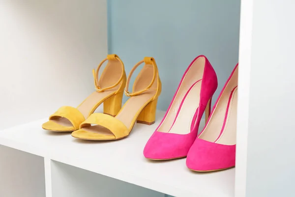 Shelf unit with stylish shoes near color wall — Stock Photo, Image