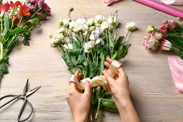 Женщина-флористка делает красивый букет за столом
