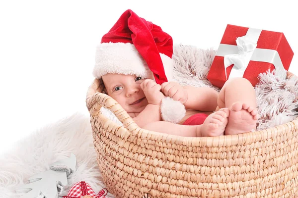 Bebê bonito com chapéu de Papai Noel e presente de Natal deitado em cesta no fundo branco — Fotografia de Stock