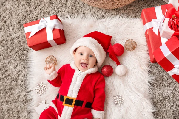 Niedliches kleines Baby im Weihnachtsmann-Kostüm und mit Weihnachtsgeschenkschachteln auf Plaid liegend, von oben gesehen — Stockfoto