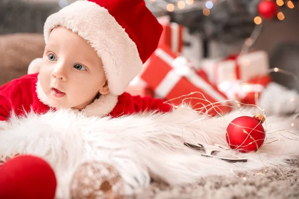 Bonito bebê em traje de Papai Noel deitado em xadrez em casa — Fotografia de Stock