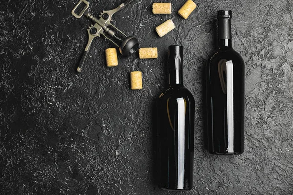 Μπουκάλια νόστιμο κρασί και φελλοί σε σκούρο φόντο — Φωτογραφία Αρχείου