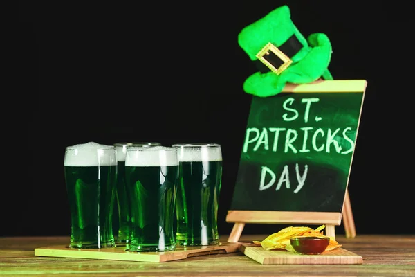 Зелене пиво, капелюх Лепрекона і дошка з текстом St. Patrick'S Day на столі — стокове фото