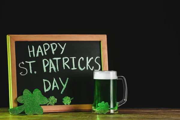 Green beer and board with text HAPPY ST. PATRICK'S DAY on table — Stock Photo, Image