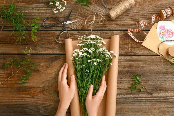 Female florist making beautiful bouquet on wooden background — Stock Photo, Image