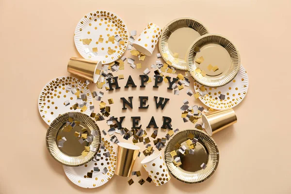 Text HAPPY NEW YEAR with tableware and confetti on color background — Stock Photo, Image