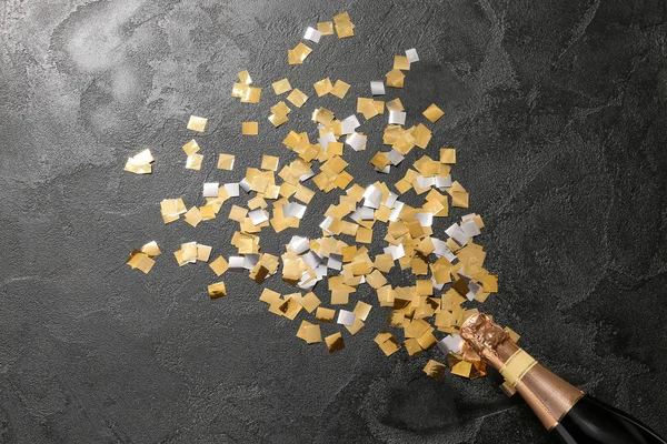Bottle of champagne with confetti on dark background — Stock Photo, Image
