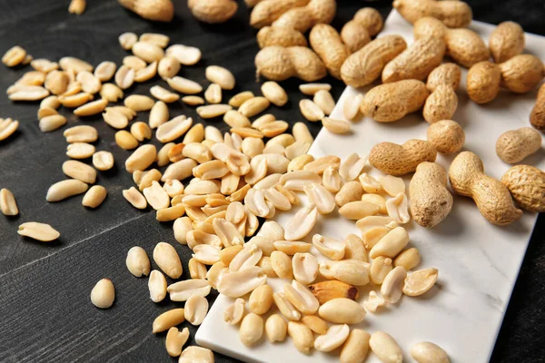 Board with peanuts on dark background — Stock Photo, Image