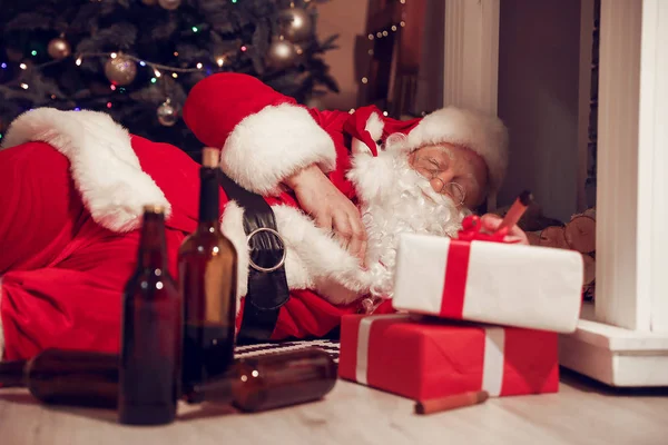 Śmieszny pijany Święty Mikołaj leżący na podłodze przy kominku — Zdjęcie stockowe