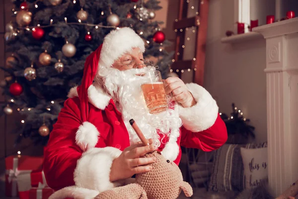 Grappige Kerstman die thuis bier drinkt en sigaren rookt — Stockfoto