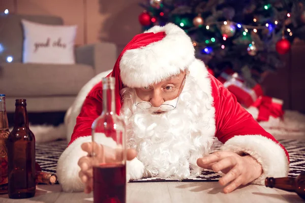 술취한 산타클로스 가 바닥에 누워 맥주를 마시려고 손을 뻗치는 모습 — 스톡 사진