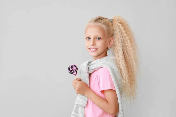 Cute little girl with lollipops on light background — Stock Photo, Image