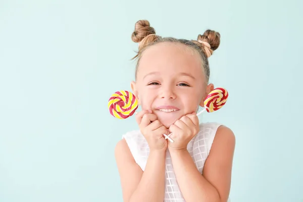 Niedliches kleines Mädchen mit süßen Lutschern auf farbigem Hintergrund — Stockfoto
