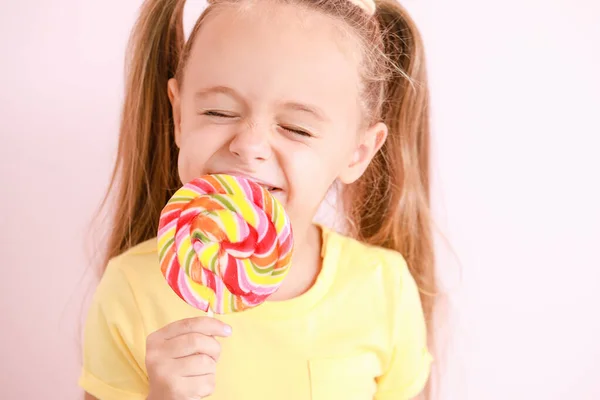 Cute little girl with sweet lollipop on color background — ストック写真