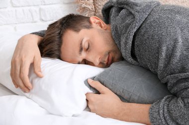 Yatakta uyuyan bornozlu yakışıklı adam.