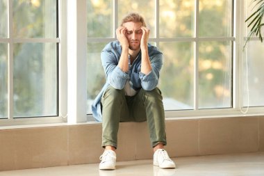 Evde pencere yakınındaki depresif adam