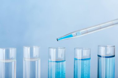 Renk arkaplanına karşı test tüpüne renk örneği damlatılıyor