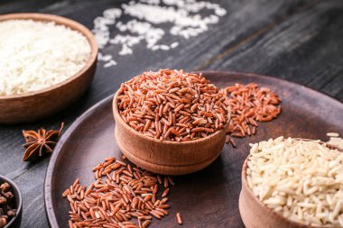 Tahta masada farklı çiğ pirinçlerle dolu kaseler.