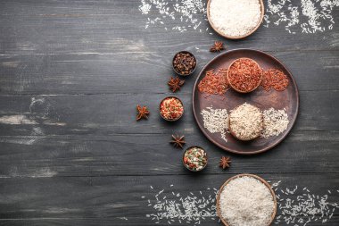Farklı çiğ pirinç, baharatlar ve ahşap masada kuru sebzeler.