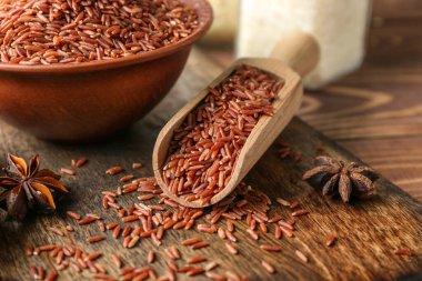 Tahta tahtada çiğ pirinç ve baharatla kepçe ve kase, yakın plan.