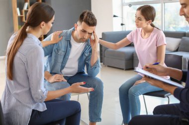 Psikolojik destek seansı sırasında üzgün adamı sakinleştiren gençler