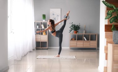 Güzel genç bayan evde yoga yapıyor.