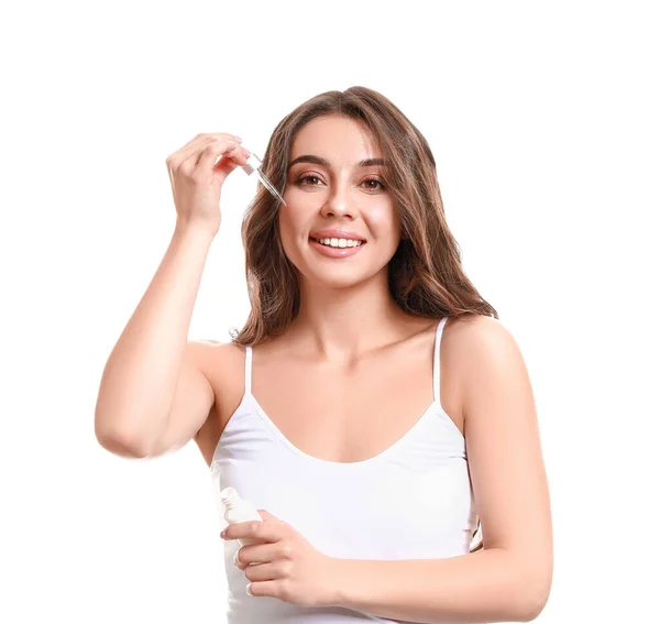 Vacker ung kvinna applicera serum på huden mot vit bakgrund — Stockfoto