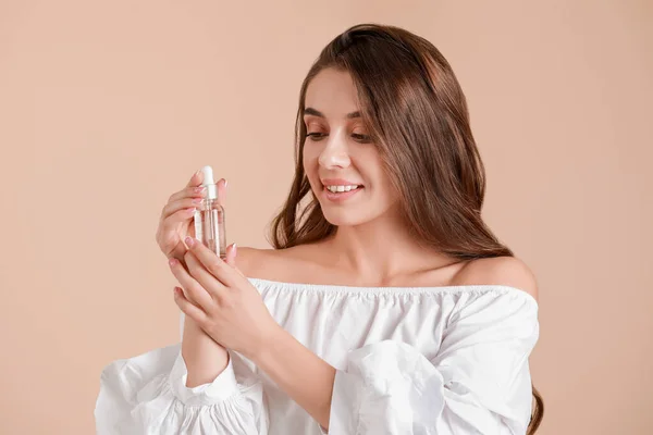 Hermosa joven con botella de suero sobre fondo claro —  Fotos de Stock