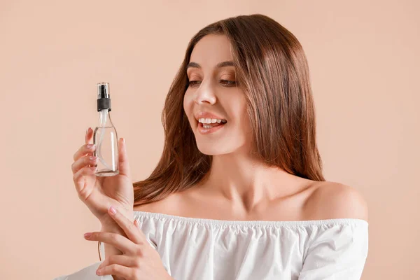 Mulher bonita com garrafa de cosméticos no fundo claro — Fotografia de Stock