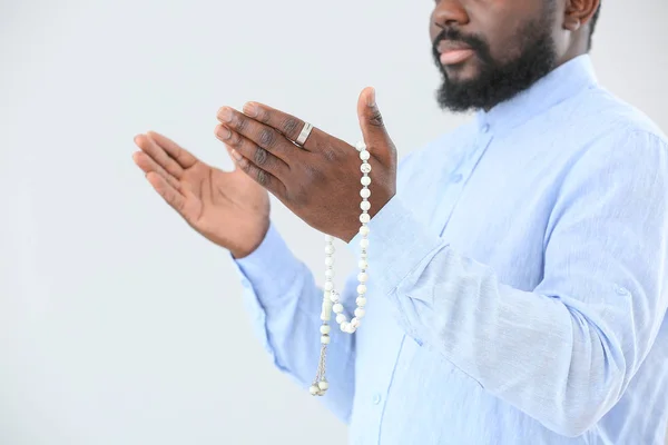 African-American Muslim man praying against light background