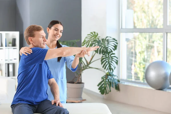 Fisioterapeuta trabajando con paciente masculino en centro de rehabilitación —  Fotos de Stock