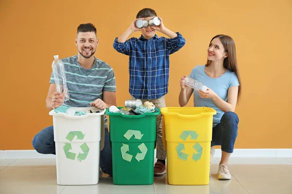 Gelukkige familie met containers voor vuilnis op kleur achtergrond. Concept van recycling — Stockfoto