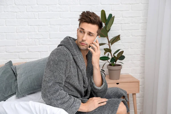 Sleepy man talking by mobile phone in bedroom — Stock Photo, Image