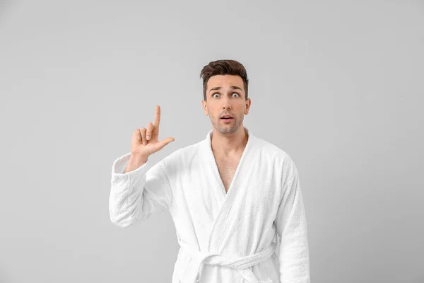 Surprised man in bathrobe pointing at something on grey background — Stock Photo, Image