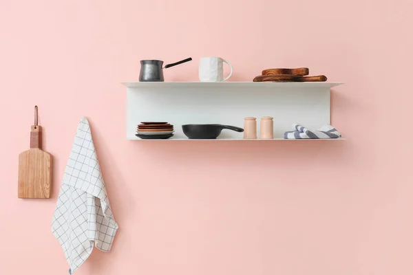 Shelf with utensils hanging on color wall — Stock Photo, Image