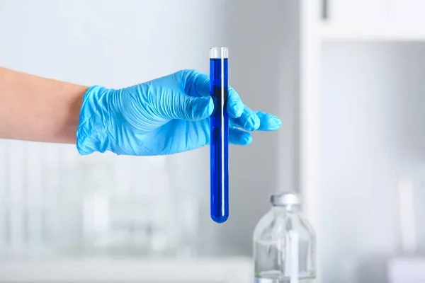 Mão de cientista segurando tubo de ensaio com amostra em laboratório — Fotografia de Stock