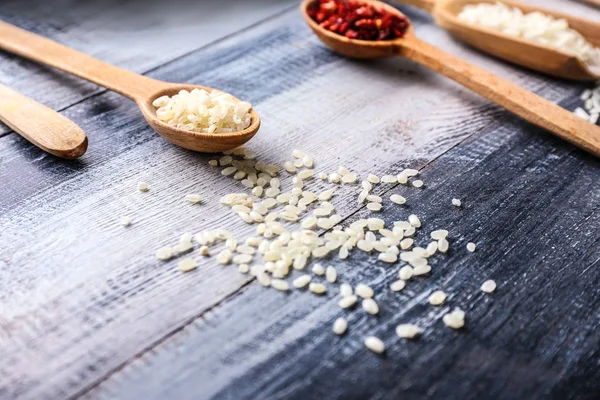 Spoon with raw rice on wooden table — Stock Photo, Image