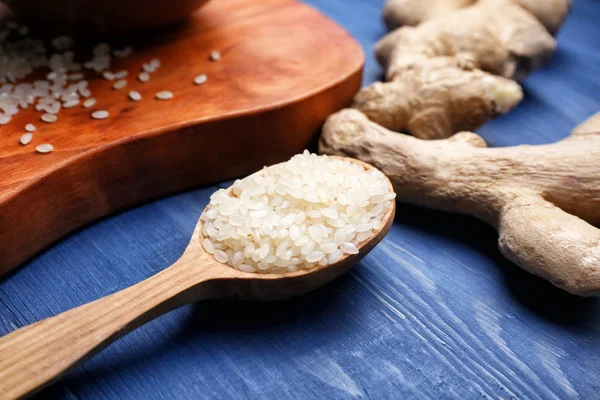 Spoon with raw rice and ginger on table — Stock Photo, Image