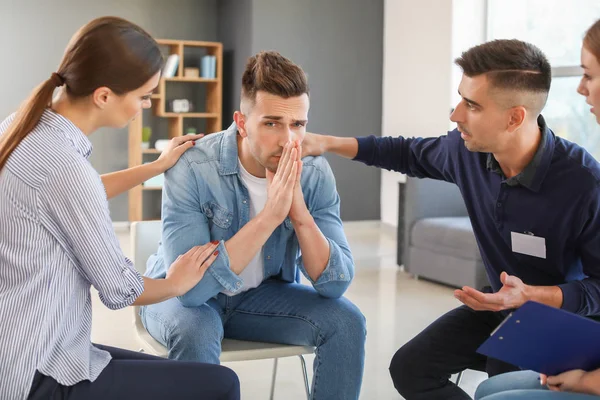 Young people calming sad man during psychological support session — Stock Photo, Image