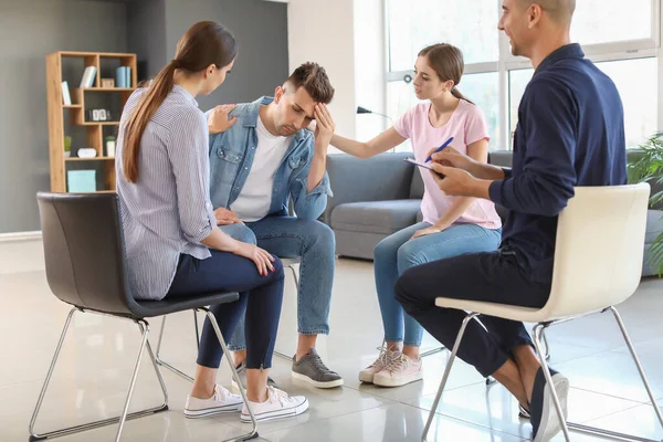 Young people calming sad man during psychological support session — ストック写真